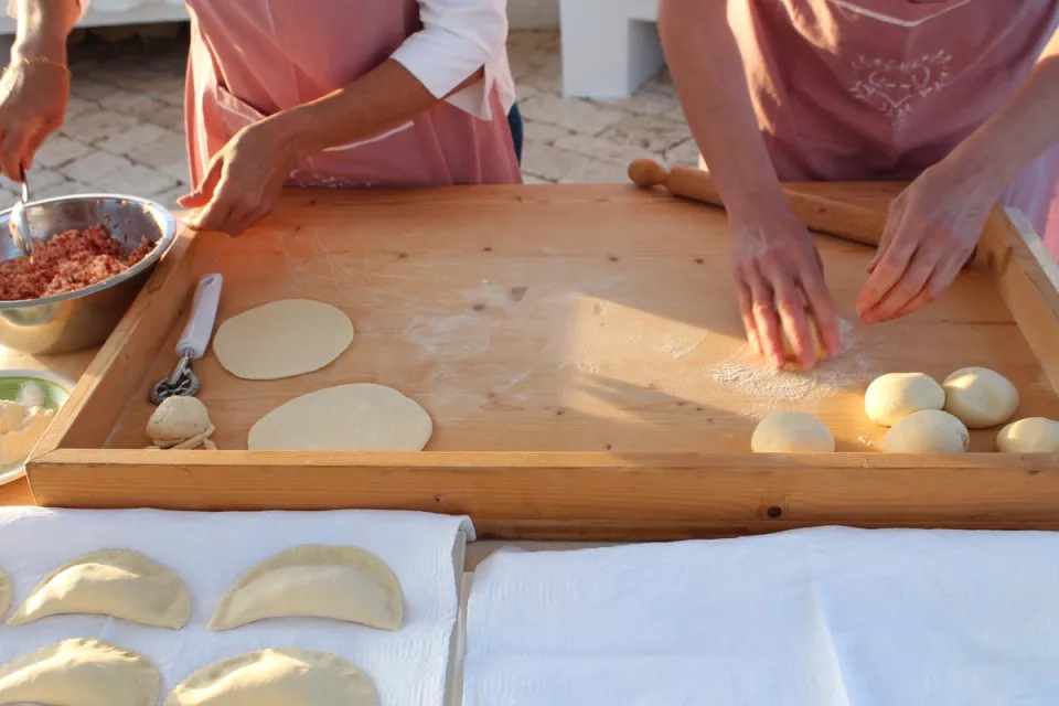 Mani che preparano i panzerotti su una spianatoia di legno